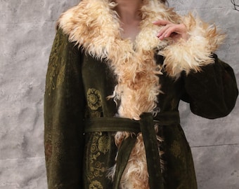 May include: A long, olive green coat with a faux fur collar and cuffs. The coat features a matching belt and intricate gold-colored floral patterns. The faux fur is a light tan color, creating a striking contrast with the dark green fabric.