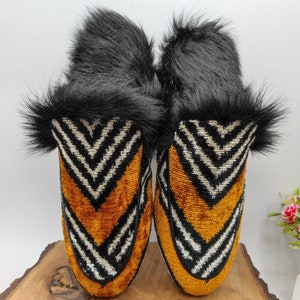 Puede incluir: Un par de zapatillas de terciopelo con estampado en blanco y negro con forro de piel negra. Las zapatillas tienen una punta puntiaguda y un tac&oacute;n bajo.