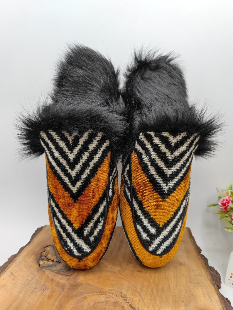 Puede incluir: Un par de zapatillas de terciopelo con estampado en blanco y negro con forro de piel negra. Las zapatillas tienen una punta puntiaguda y un tac&oacute;n bajo.