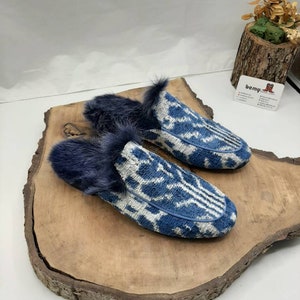 May include: A pair of blue and white patterned slippers with a fuzzy blue lining. The slippers are on a wooden surface.