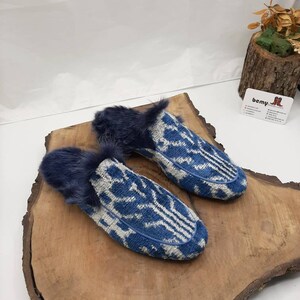 May include: A pair of blue and white patterned slippers with a fuzzy lining. The slippers are on a wooden surface.