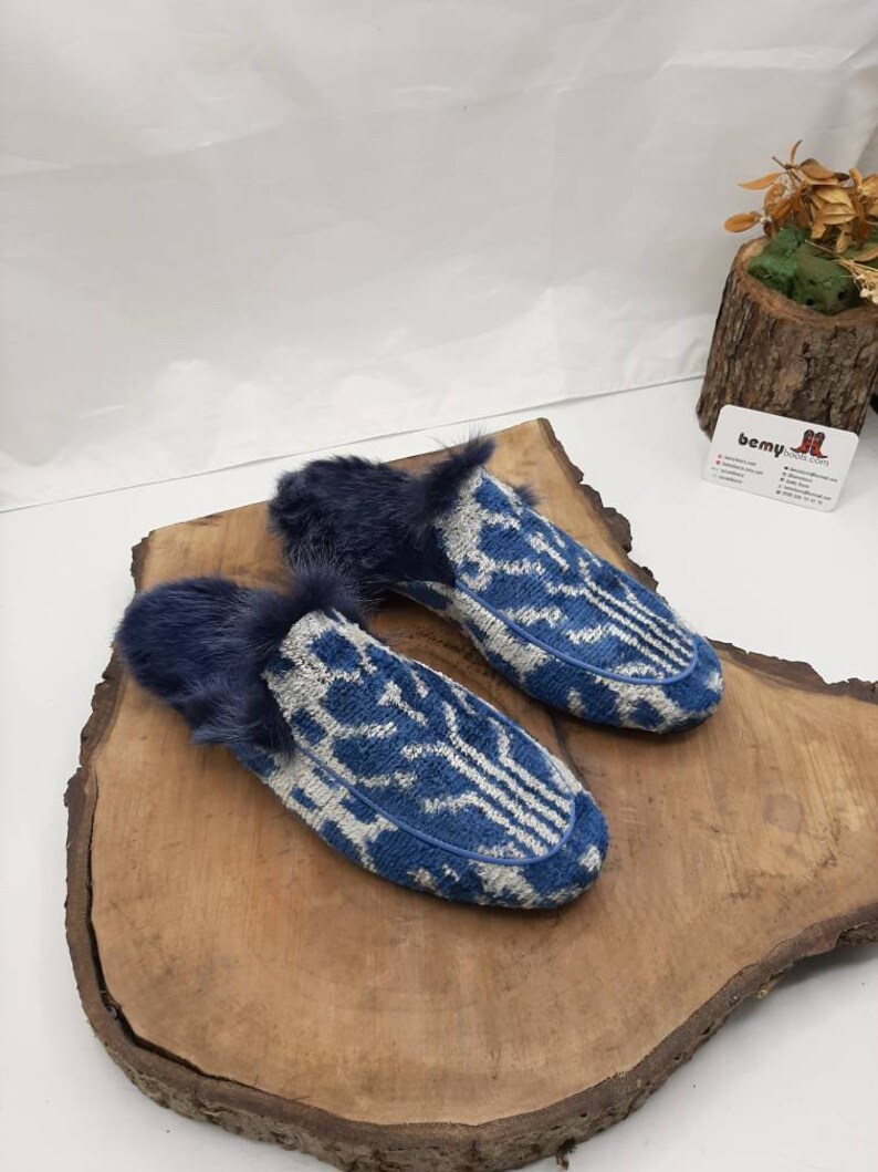 May include: A pair of blue and white patterned slippers with a fuzzy lining. The slippers are on a wooden surface.