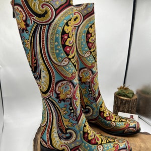 May include: A pair of tall black boots with a paisley pattern in shades of blue, red, gold, and white. The boots have a pointed toe and a low heel.