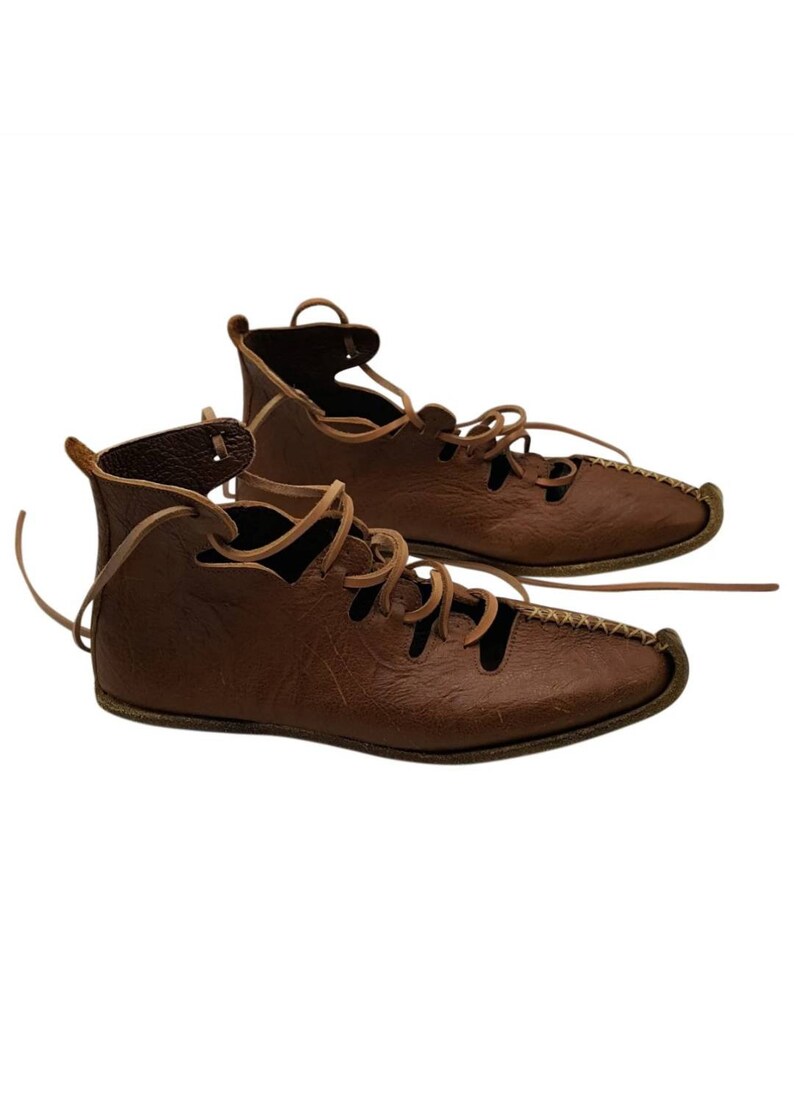 May include: A pair of brown leather lace-up sandals with a pointed toe. The sandals have a simple design with multiple holes for ventilation.