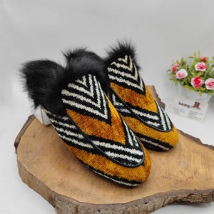 Puede incluir: Un par de zapatillas de terciopelo rayadas en blanco y negro con un patr&oacute;n de chevron amarillo y ribete de piel negra.