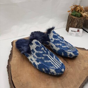 May include: A pair of blue and white patterned slippers with a fuzzy lining. The slippers are on a wooden surface.