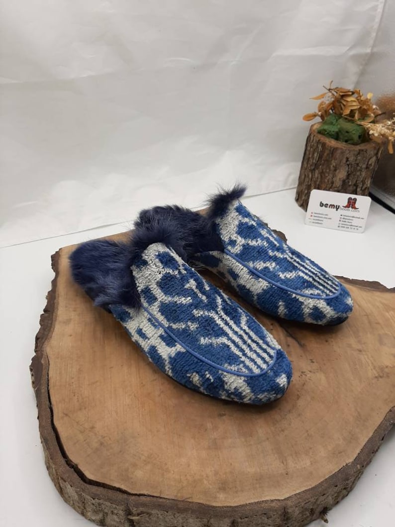 May include: A pair of blue and white patterned slippers with a fuzzy lining. The slippers are on a wooden surface.