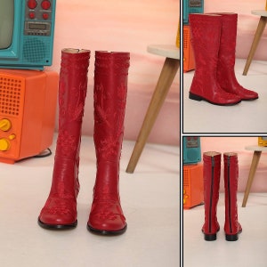 Puede incluir: Un par de botas rojas hasta la rodilla con bordados florales. Las botas tienen punta redonda y tac&oacute;n peque&ntilde;o. El bordado es detallado y cubre la parte delantera y los laterales de las botas. Las botas tienen cierre de cremallera en la parte trasera.