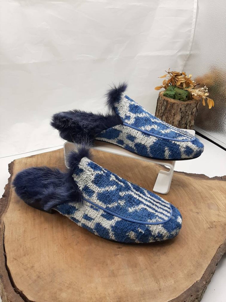 May include: A pair of blue and white patterned slippers with a fuzzy lining. The slippers are made of a soft, plush fabric and have a comfortable fit.