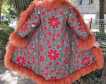 May include: A long, green jacket with a red floral pattern and a brown fur trim. The jacket is made of a soft, comfortable fabric and has a relaxed fit.