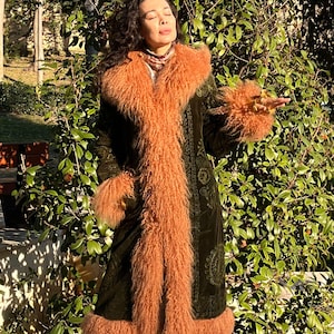 May include: A long, green velvet coat with a brown fur collar and cuffs. The coat has a paisley pattern and is lined with a brown fur.