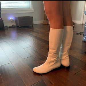 Puede incluir: Un par de botas blancas de ca&ntilde;a alta hasta la rodilla con punta puntiaguda y tac&oacute;n bajo.