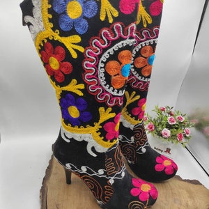 Peut inclure: Bottines noires à talons hauts avec des broderies florales colorées. Les bottes ont une pointe pointue et un talon épais.
