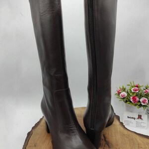 May include: A pair of brown leather knee-high boots with a block heel and a zipper on the inside of each boot.