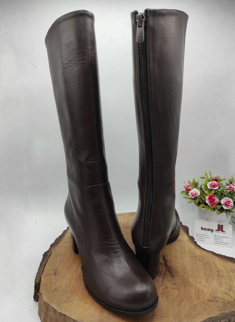 May include: A pair of brown leather knee-high boots with a block heel and a zipper on the inside of each boot.