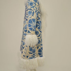 May include: A long white coat with a blue floral pattern and white fur trim around the collar, cuffs, and hem.