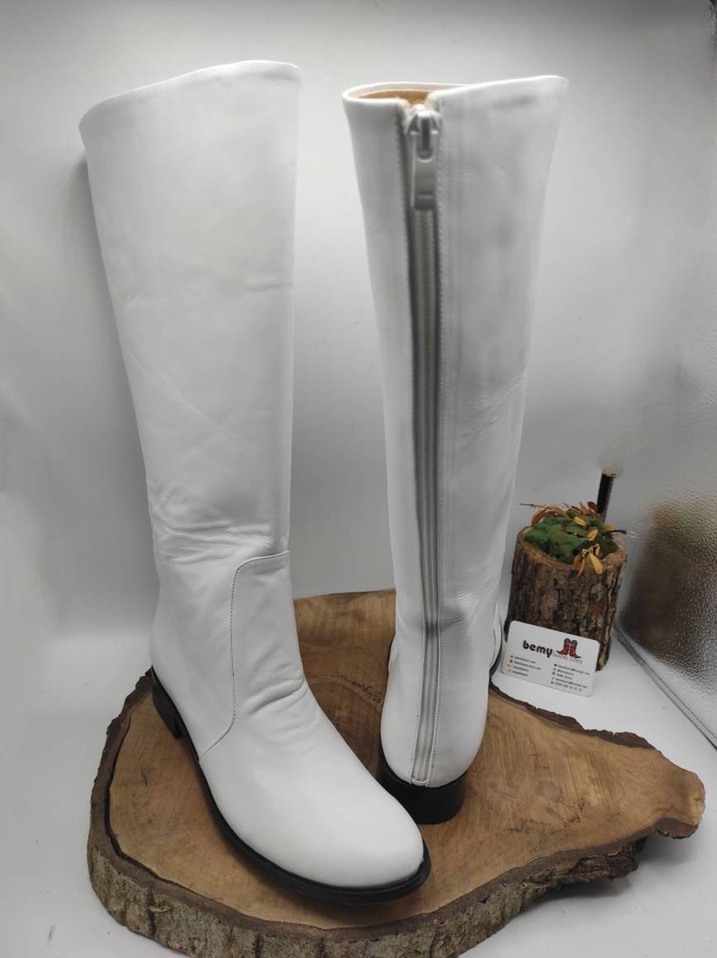 Puede incluir: Un par de botas blancas de cuero por encima de la rodilla con una cremallera en el interior de cada bota. Las botas tienen una punta puntiaguda y un tac&oacute;n bajo.