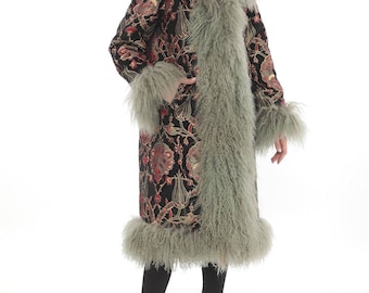 May include: A long black coat with a floral pattern and a green fur trim. The coat has a collar and cuffs made of the same fur.