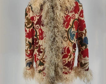 May include: Cream-colored jacket with red, green, and blue floral embroidery. The jacket features a fluffy, cream-colored collar and cuffs. The jacket is displayed on a white mannequin.