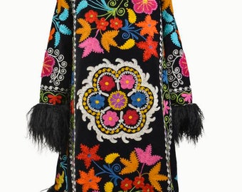 May include: A black velvet coat with a long, full cut and a fluffy black fur collar and cuffs. The coat is embroidered with colorful floral designs in shades of pink, red, orange, yellow, green, blue, and white.