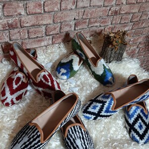 May include: Five pairs of women's slip-on shoes with different patterned fabric uppers. The shoes are all in a similar style, with a pointed toe and a low heel. The patterns include red and white, blue and white, green and white, and black and white.