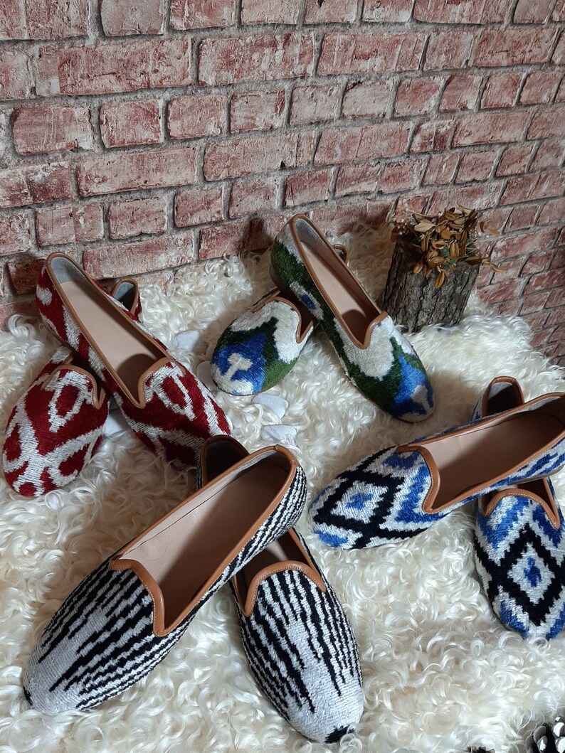 May include: Five pairs of women's slip-on shoes with different patterned fabric uppers. The shoes are all in a similar style, with a pointed toe and a low heel. The patterns include red and white, blue and white, green and white, and black and white.