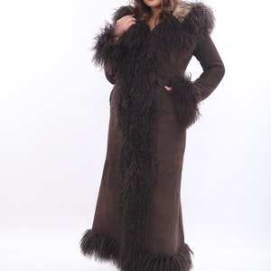 May include: A long brown suede coat with a natural fur trim around the hood, collar, cuffs, and hem.