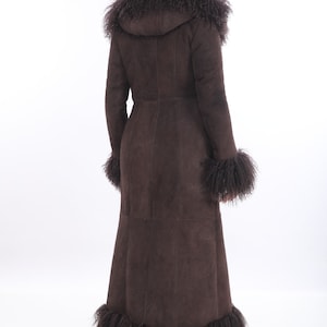 May include: A long brown suede coat with a fur trim around the hood, cuffs, and hem.