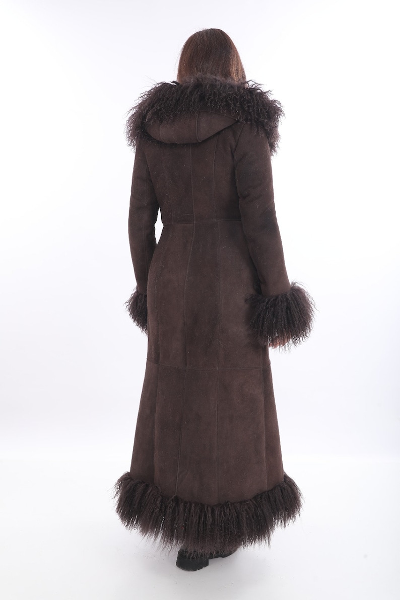 May include: A long brown suede coat with a fur trim around the hood, cuffs, and hem.