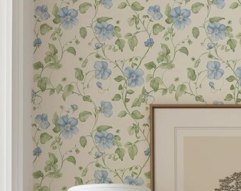 Könnte beinhalten: Eine weiße Kommode mit drei Schubladen und braunen Holzbeinen und -oberteil. Die Kommode ist mit einer weißen Lampe mit weißem Lampenschirm, einem gerahmten Druck eines Baumes und einem Stapel Büchern dekoriert. Die Kommode steht vor einer Wand mit einer floralen Tapetenmuster mit blauen Blumen und grünen Blättern.