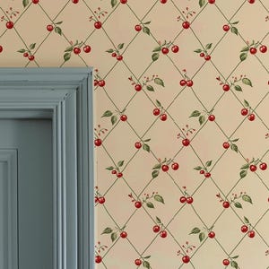 Può includere: Interno di una stanza con porta e boiserie azzurro chiaro. La carta da parati ha uno sfondo color crema con un motivo ripetuto di ciliegie rosse e foglie verdi disposte a griglia a rombi. La porta ha una maniglia in ottone.