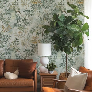 May include: A living room with a brown leather sofa and armchair, a white lamp, a potted plant, and a woven basket. The wall is covered in a green and yellow floral wallpaper.