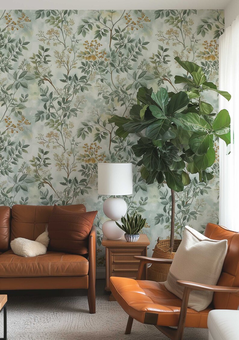 May include: A living room with a brown leather sofa and armchair, a white lamp, a potted plant, and a woven basket. The wall is covered in a green and yellow floral wallpaper.