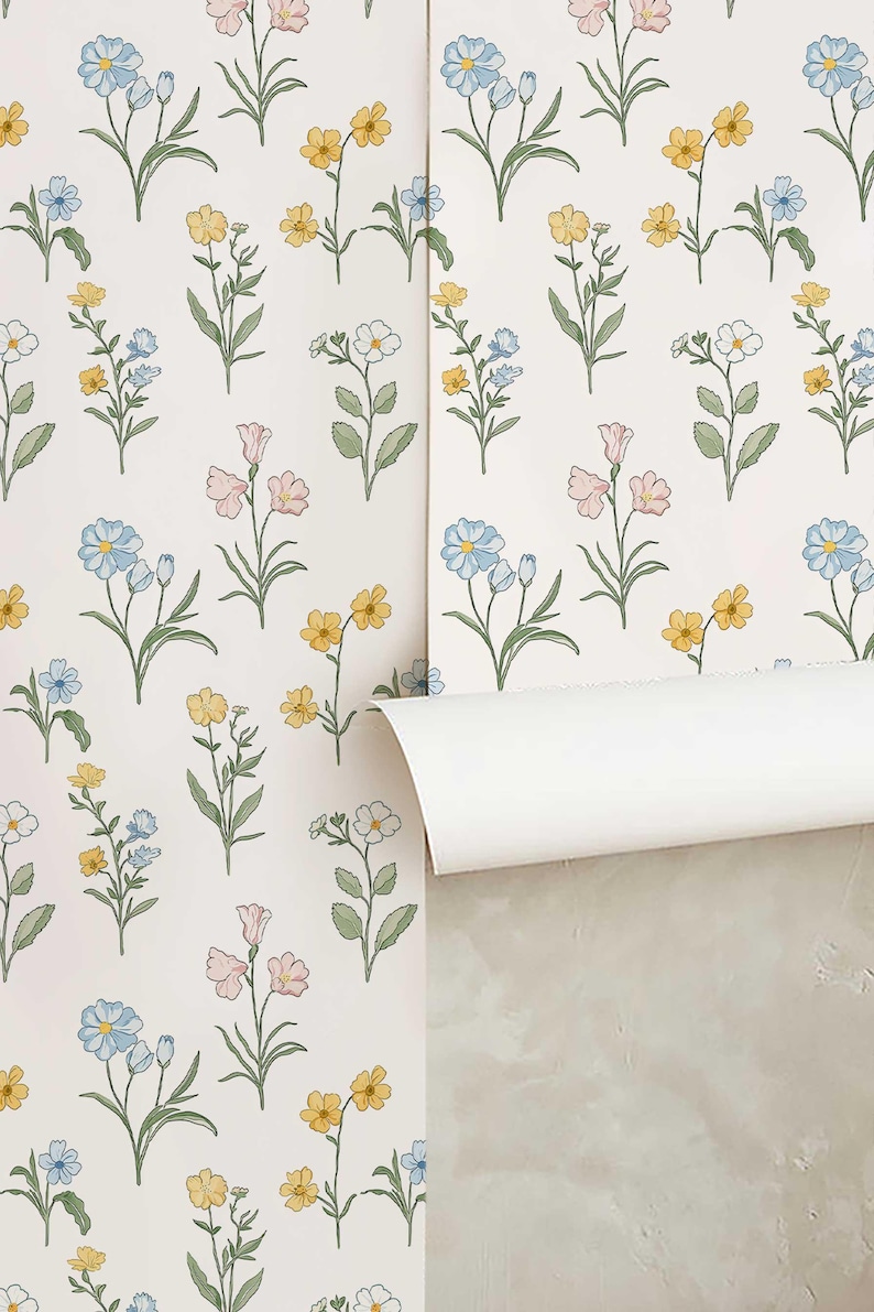 May include: Wallpaper featuring a repeating pattern of delicate wildflowers on a white background. The botanical illustrations include small blue, yellow, and pink flowers with green stems and leaves, arranged in a simple, spaced-out layout.