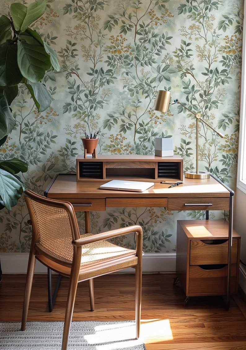 May include: A wooden desk with a woven chair, a lamp, and a small wooden file cabinet. The desk has a laptop and a potted plant on it. The wall behind the desk has a green and brown floral wallpaper.
