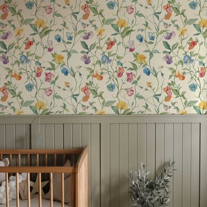 May include: Wallpaper featuring a repeating botanical pattern of colorful sweet pea flowers in shades of red, yellow, purple, and blue with green vines on a cream background, positioned above a sage green vertical paneled wainscoting wall.