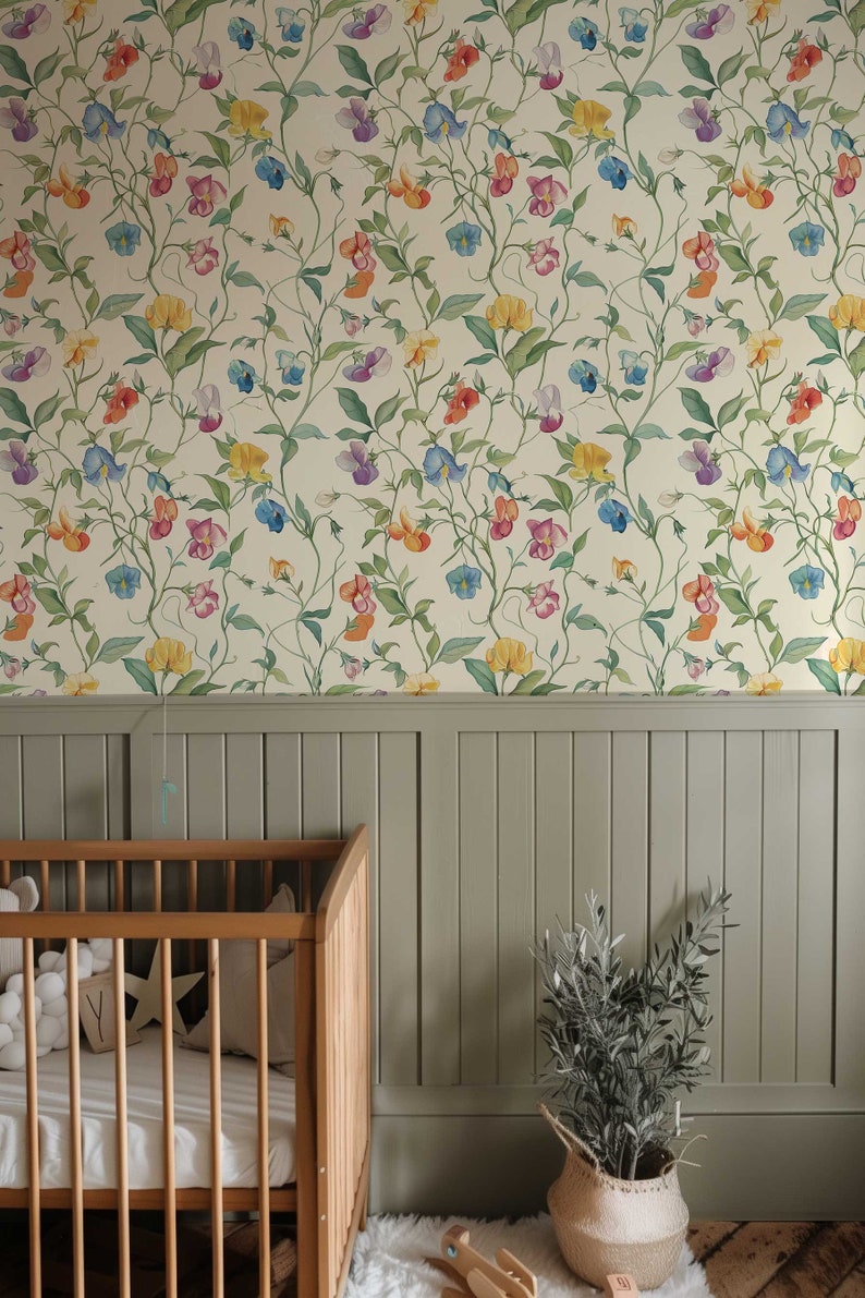 May include: Wallpaper featuring a repeating botanical pattern of colorful sweet pea flowers in shades of red, yellow, purple, and blue with green vines on a cream background, positioned above a sage green vertical paneled wainscoting wall.