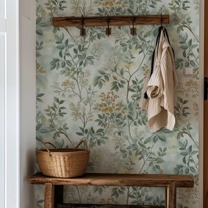 May include: A wooden bench with a woven basket and a white sweater hanging on a wooden rack against a wall with a green and yellow floral wallpaper.