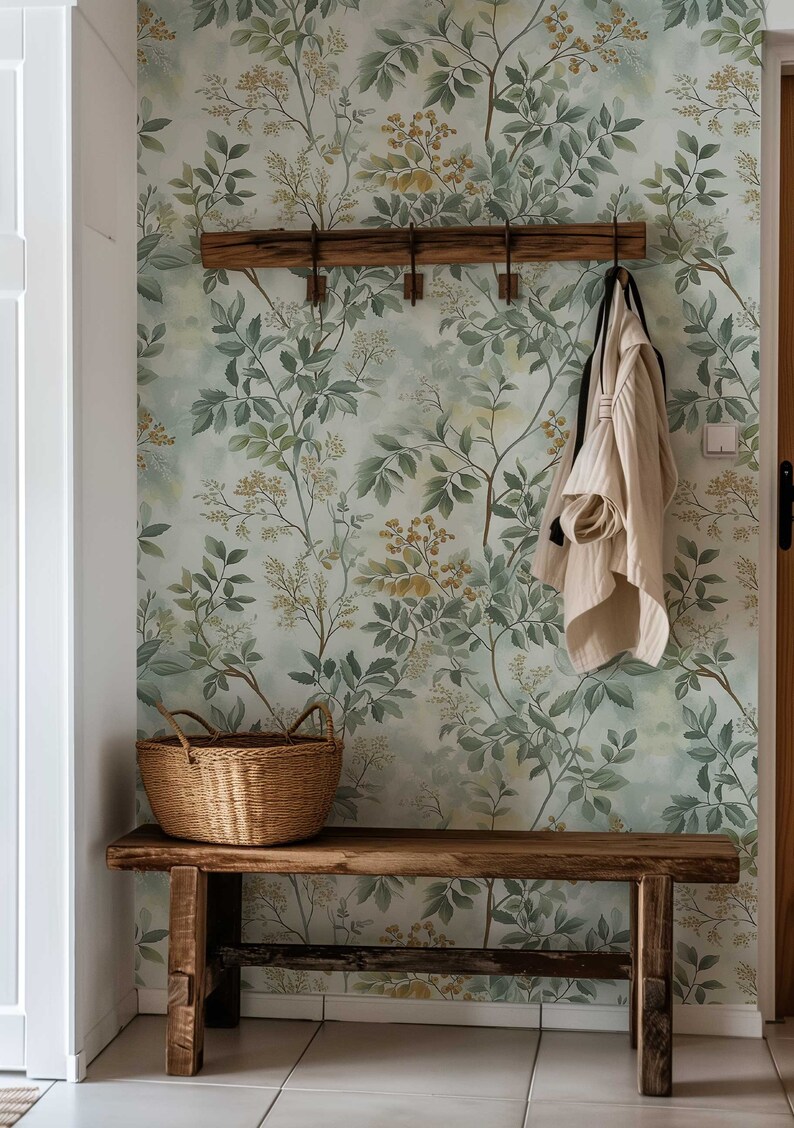 May include: A wooden bench with a woven basket and a white sweater hanging on a wooden rack against a wall with a green and yellow floral wallpaper.