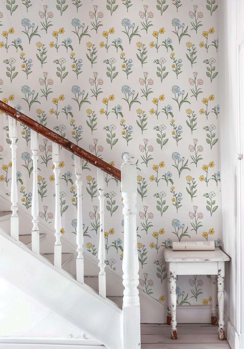 May include: Wallpaper featuring a repeating pattern of small, delicate flowers in shades of yellow, light blue, and soft pink with green stems and leaves on a white background, positioned behind a white staircase with a dark wood handrail.