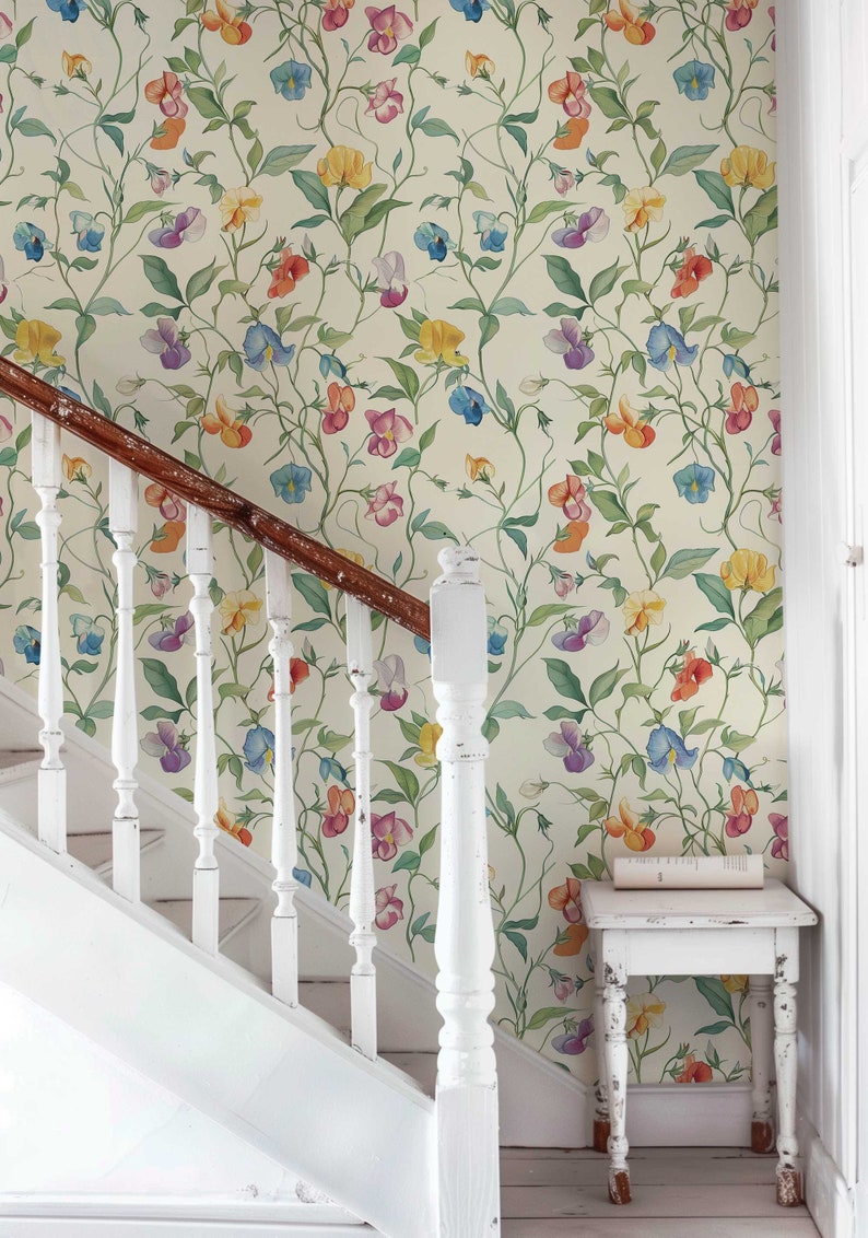 May include: A white staircase with a wooden handrail and white spindles. The wall behind the staircase is covered in a floral wallpaper with a pattern of colorful sweet pea flowers on a cream background.