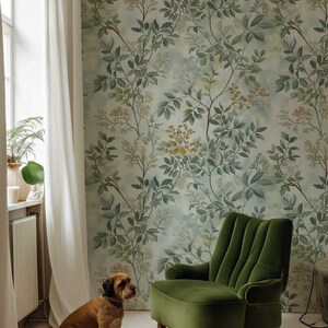 May include: A brown dog sits on a white floor in front of a green velvet armchair. The armchair is in front of a wall with a green and yellow floral wallpaper.