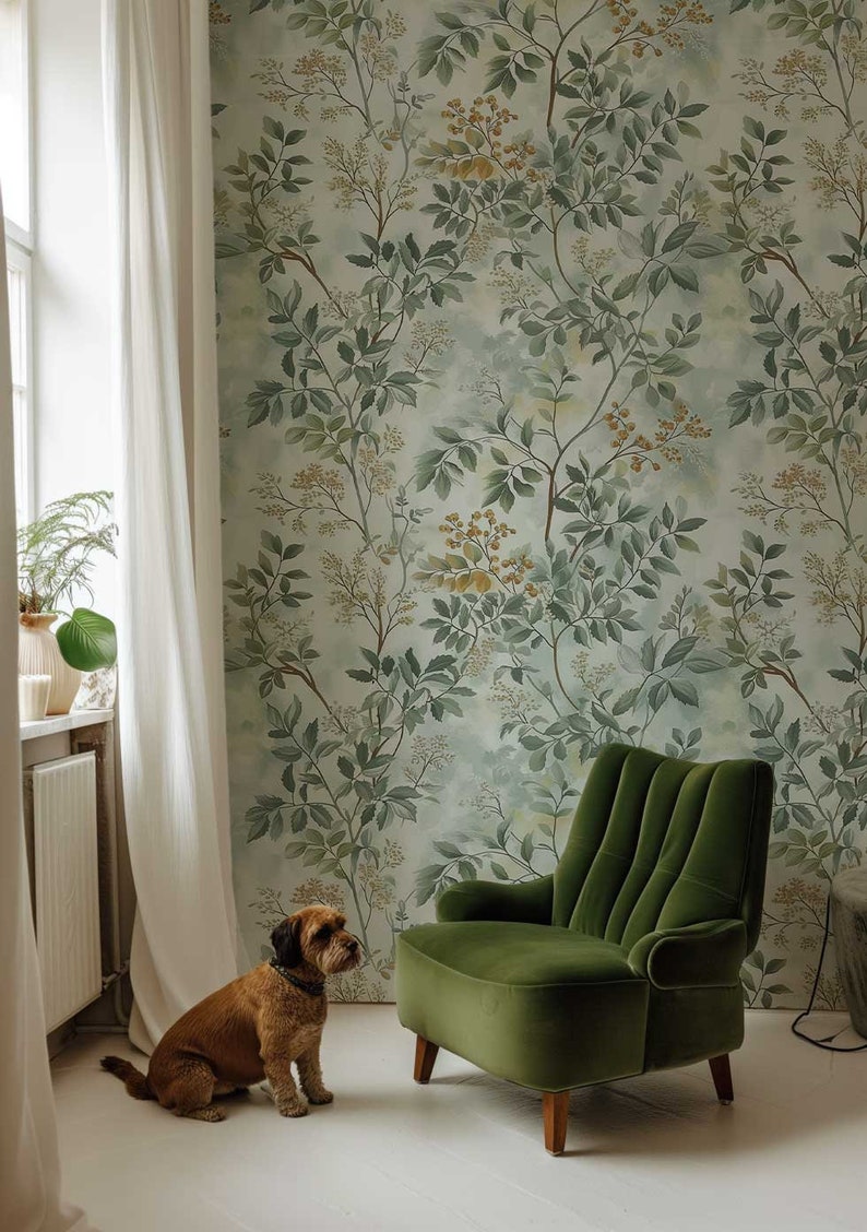 May include: A brown dog sits on a white floor in front of a green velvet armchair. The armchair is in front of a wall with a green and yellow floral wallpaper.