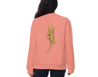 Puede incluir: Una sudadera de color coral con un diseño detallado de lagarto dorado en la espalda. La parte superior de manga larga tiene cuello redondo y un ajuste relajado, adecuado para uso casual. El gráfico del lagarto es un elemento llamativo.