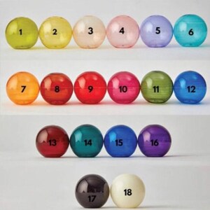 Puede incluir: Dieciocho bolas de vidrio de colores numeradas del 1 al 18. Las bolas est&aacute;n dispuestas en tres filas de seis, siendo la primera fila amarilla, verde, blanca, rosa, morada y azul. La segunda fila es naranja, roja, roja, rosa, verde y azul. La tercera fila es roja, verde, azul, morada, negra y blanca.