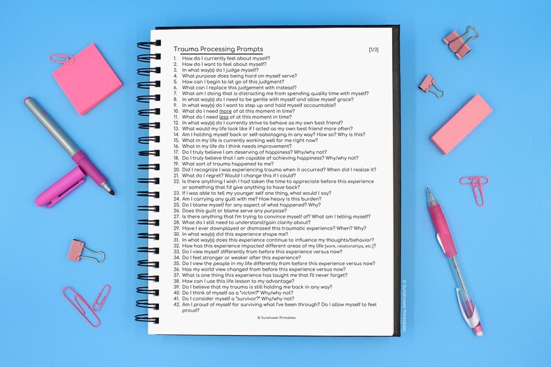 May include: A spiral bound notebook with a white cover and black text that reads "Trauma Processing Prompts". The notebook is open to a page with a list of 42 questions about trauma processing.