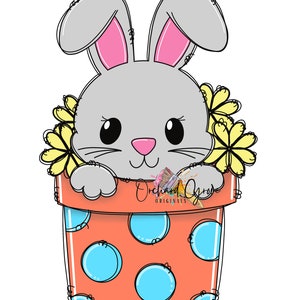 Puede incluir: Un conejo gris con orejas rosas asoma de una maceta de terracota con lunares azules. Flores amarillas rodean la cabeza del conejo. La maceta tiene el texto "Orchard Grove Originals" en el lateral.