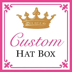 May include: A square graphic with a gold crown and the words "Custom HAT BOX" in pink and black. The design is framed by a pink border with decorative corner elements, set against a white background.