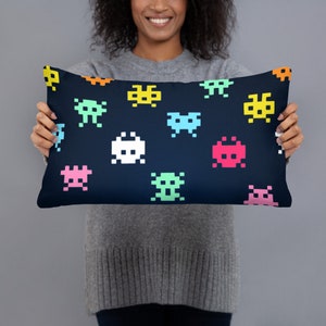 May include: A blue pillow with a repeating pattern of colorful pixelated space invaders.