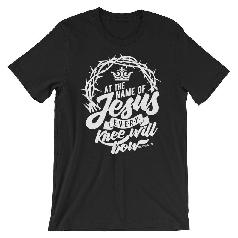 May include: Black t-shirt with a white graphic design featuring a crown of thorns, the words "At the name of Jesus every knee will bow", and the scripture reference "Philippians 2:10".